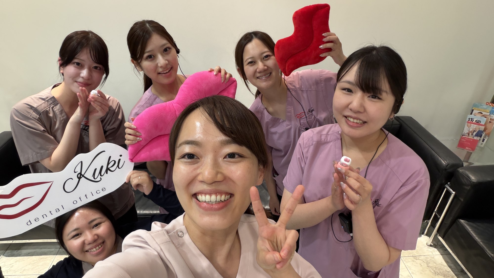医院のロゴと小物を手に笑顔で集まるスタッフ